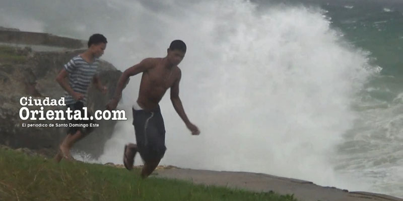 Dos hombres corren próximo a los arrecifes en la autopista Las Américas, al momento de producirse una ola rompiente al paso del huracán María