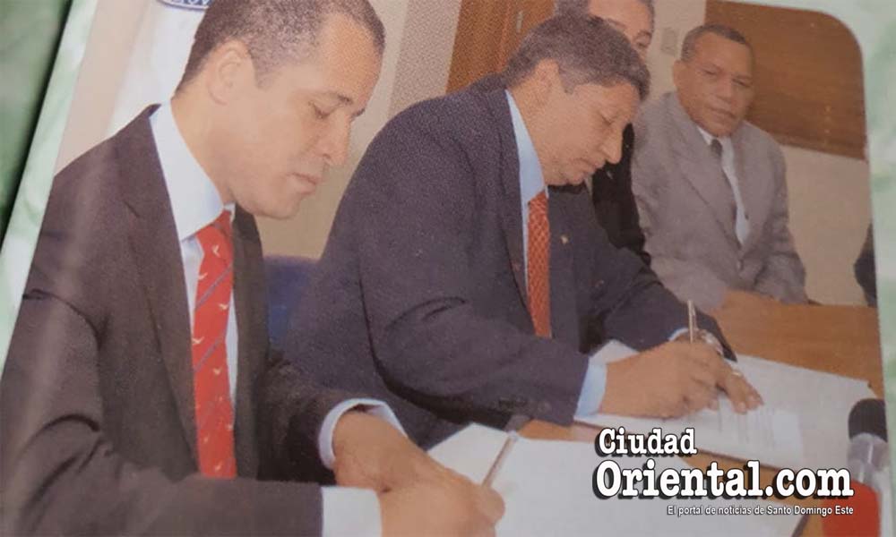 Juan De los Santos (i) y Roberto Reyna, entonces alcalde de SDE y rector de la UASD, respectivamente, firman convenio de colaboración ASDE-UASD, el 30 de Agosto de 2006