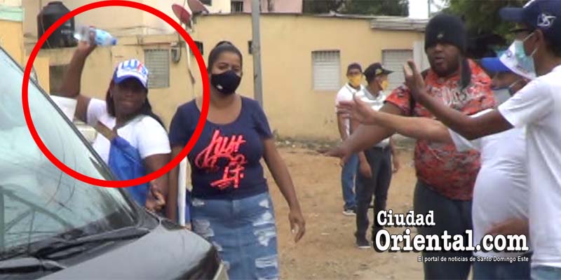 Esta mujer identificada con los simbolos dle PRM lanza un objeto a Cinthia Polanco