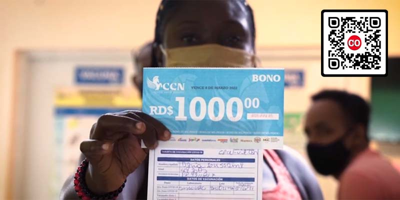 Una mujer muestra su tarjeta d evacunación junto al bono por mil pesos que le obsequió El Boli