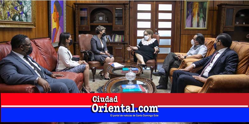 . La magistrada Miriam Germán Brito habla a la presidenta del CD de ProCompetencia, María Elena Vásquez. Observan la consejera Gianna Franjul y los consejeros Juan Reyes, Iván Gatón y Víctor Mateo.